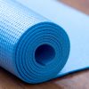 Folded blue yoga mat Close up of rolled blue yoga, pilates mat on the floor. Healthy life, keep fit concepts